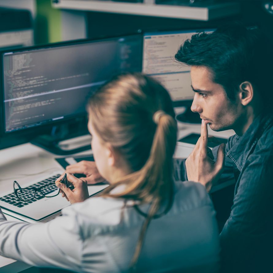 Two colleagues look at a computer to retrieve their client access data