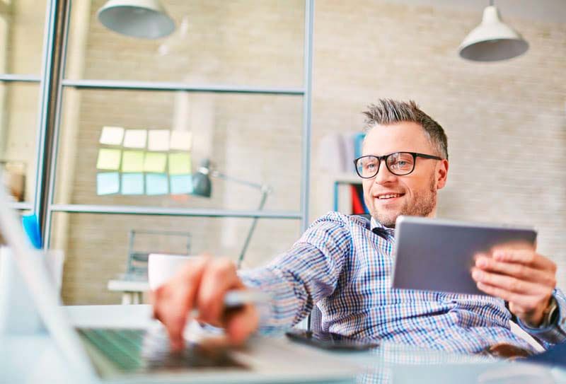Boy consults his tablet and computer to search for the data of a domain he wants to register with Whois
