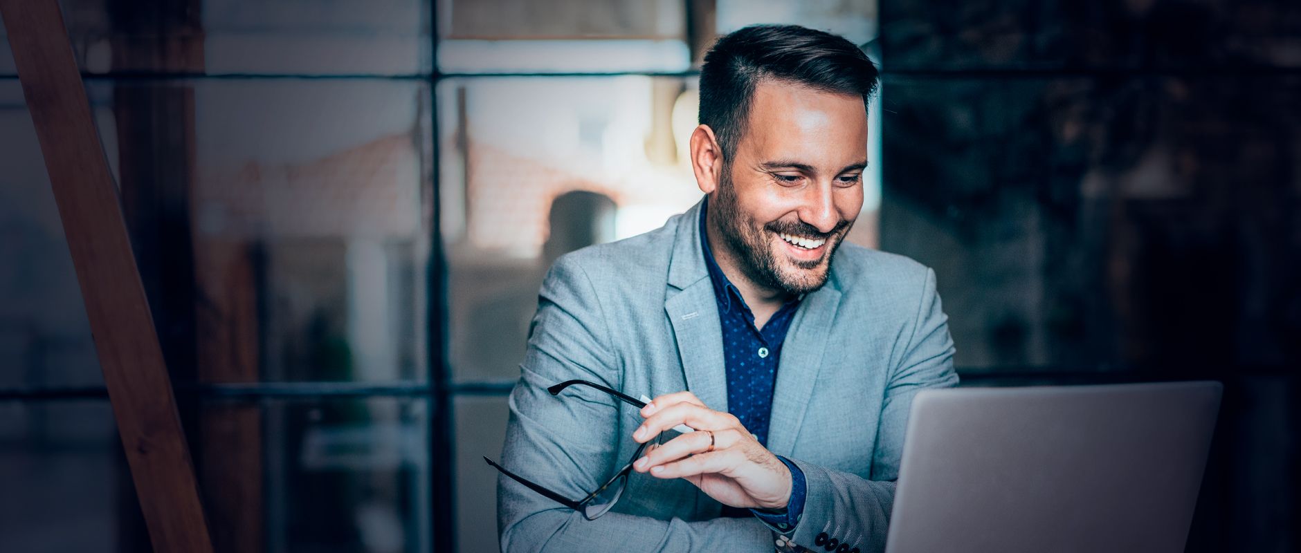 Professional smiling in front of his laptop, satisfied to have Arsys, which has more than 25 years of experience.