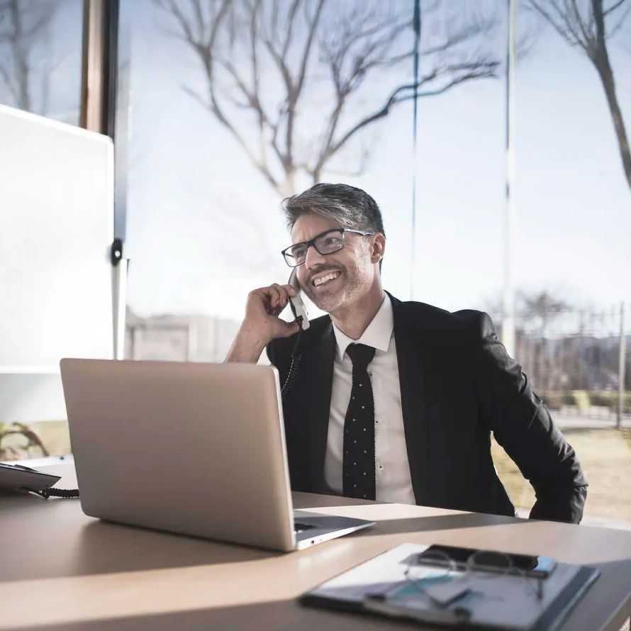 A gentleman is talking on the phone and checking his laptop, satisfied because we guarantee maximum performance and availability for his project.