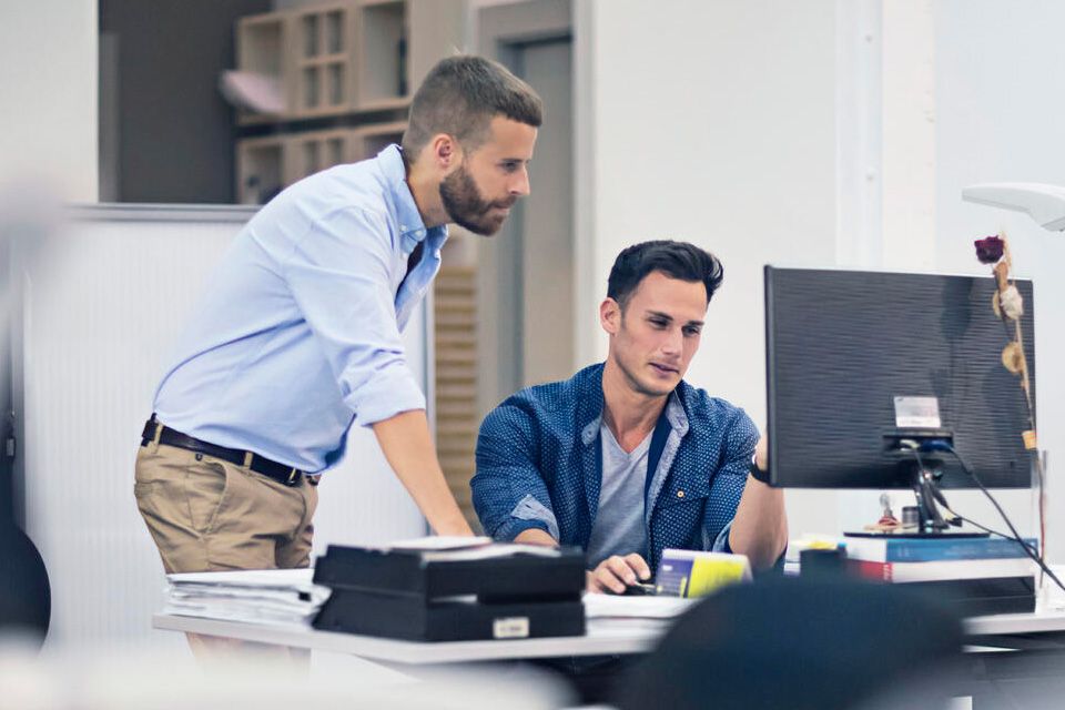 A colleague explains to another in front of a computer why it is important to have a professional antivirus for all your devices.